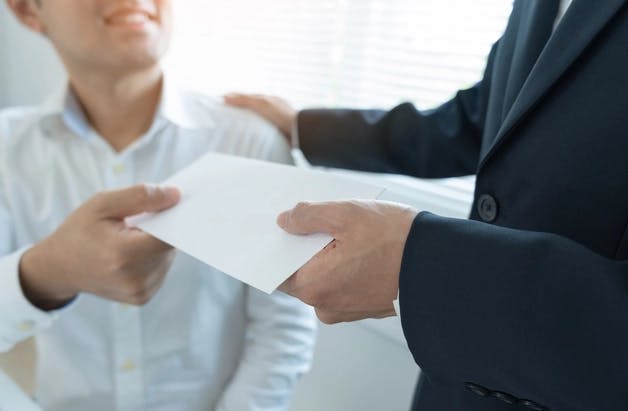 An employer handing an envelope to his employee