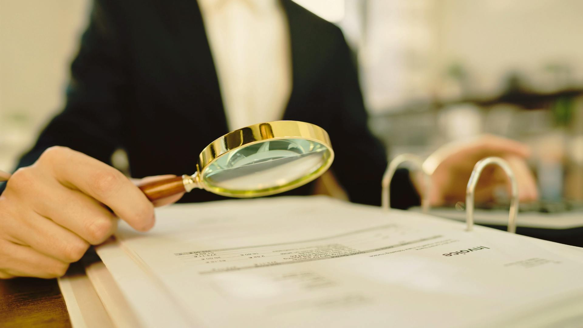 A person using magnifying glass to view a document