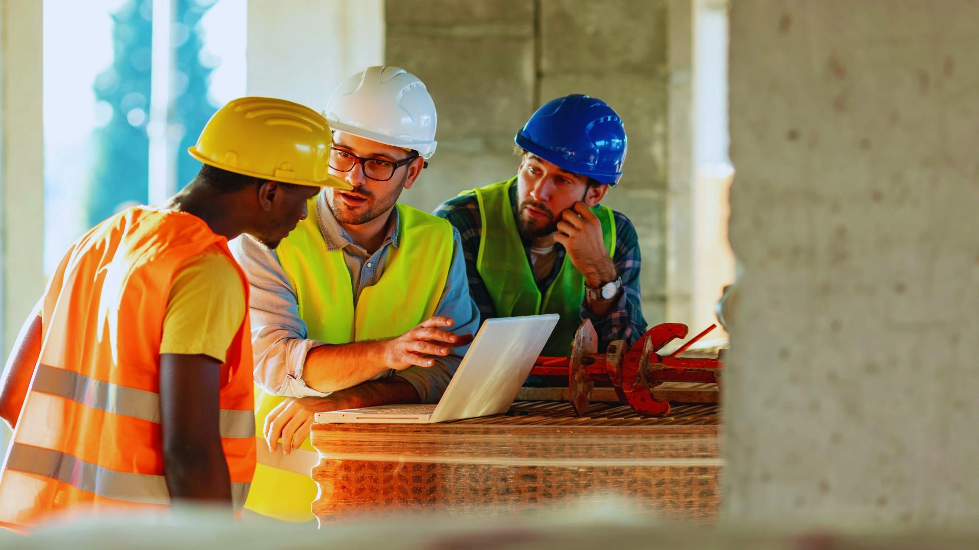 Three construction workers wearing safety vests and helmets