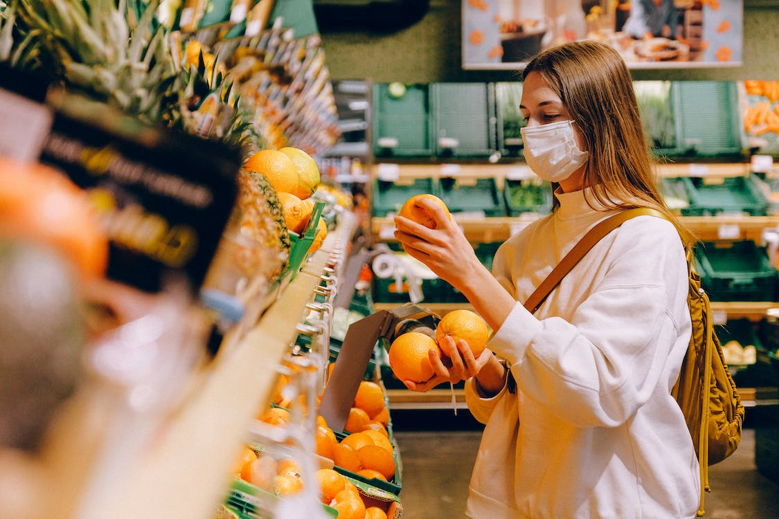  A woman in the grocery store looking at oranges